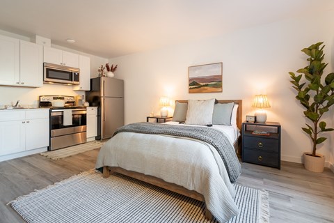 a bedroom with a bed and a kitchen with a microwave and