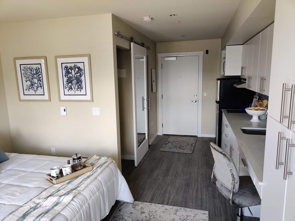 a bedroom with a bed and a desk and a kitchen