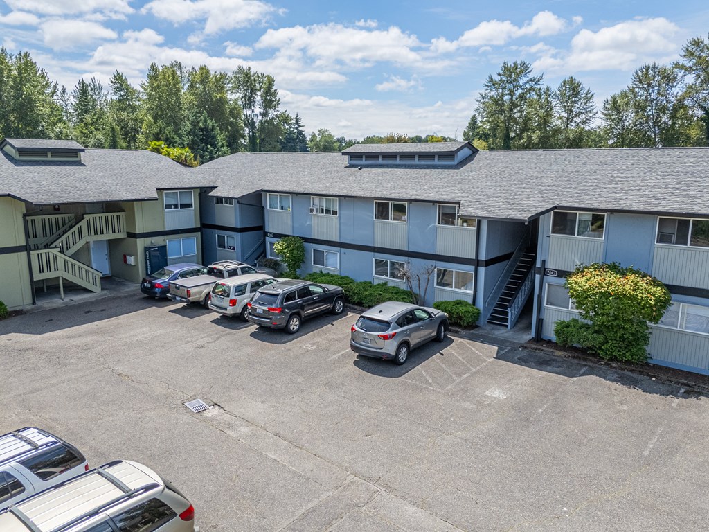 A parking lot with several cars and a building in the background.