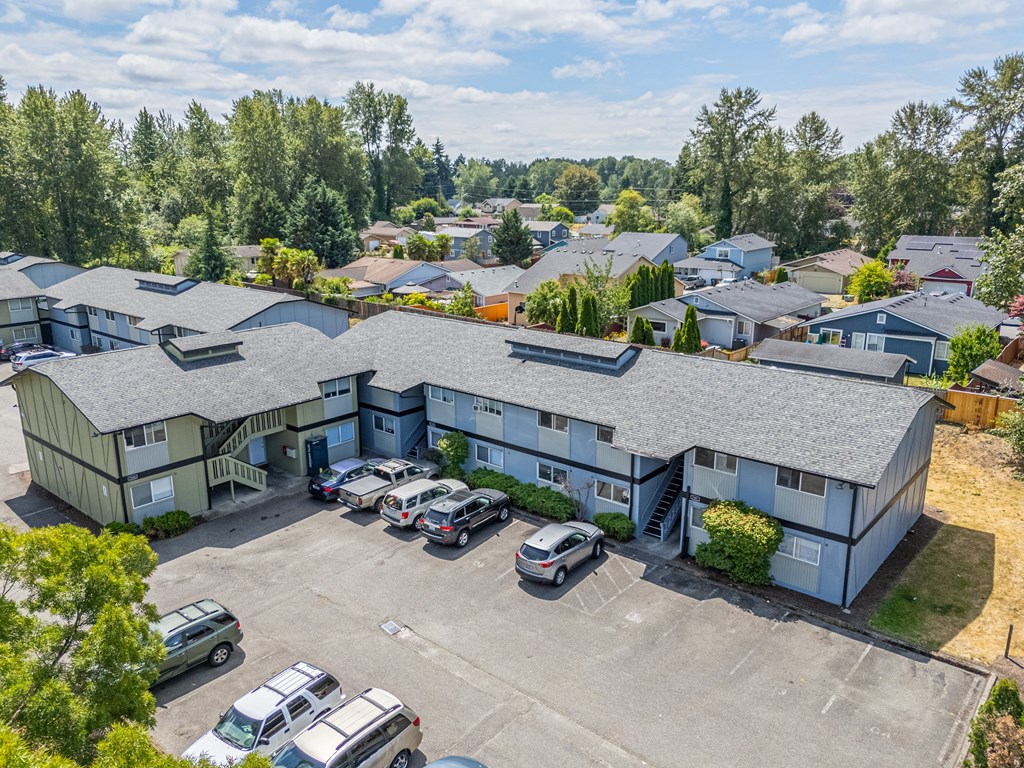A parking lot in front of a building surrounded by trees.