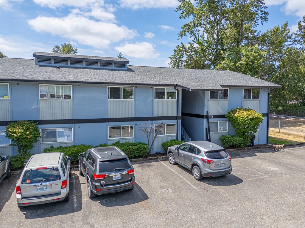 Three cars are parked in a parking lot in front of a blue building.