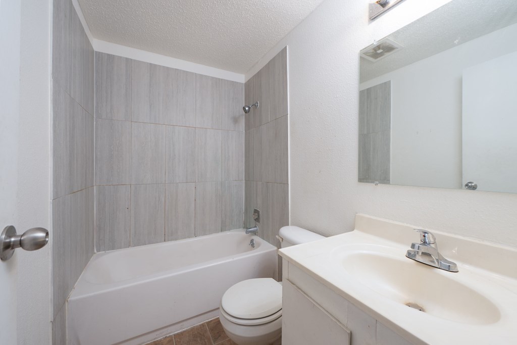 A white bathroom with a toilet, sink, and bathtub.