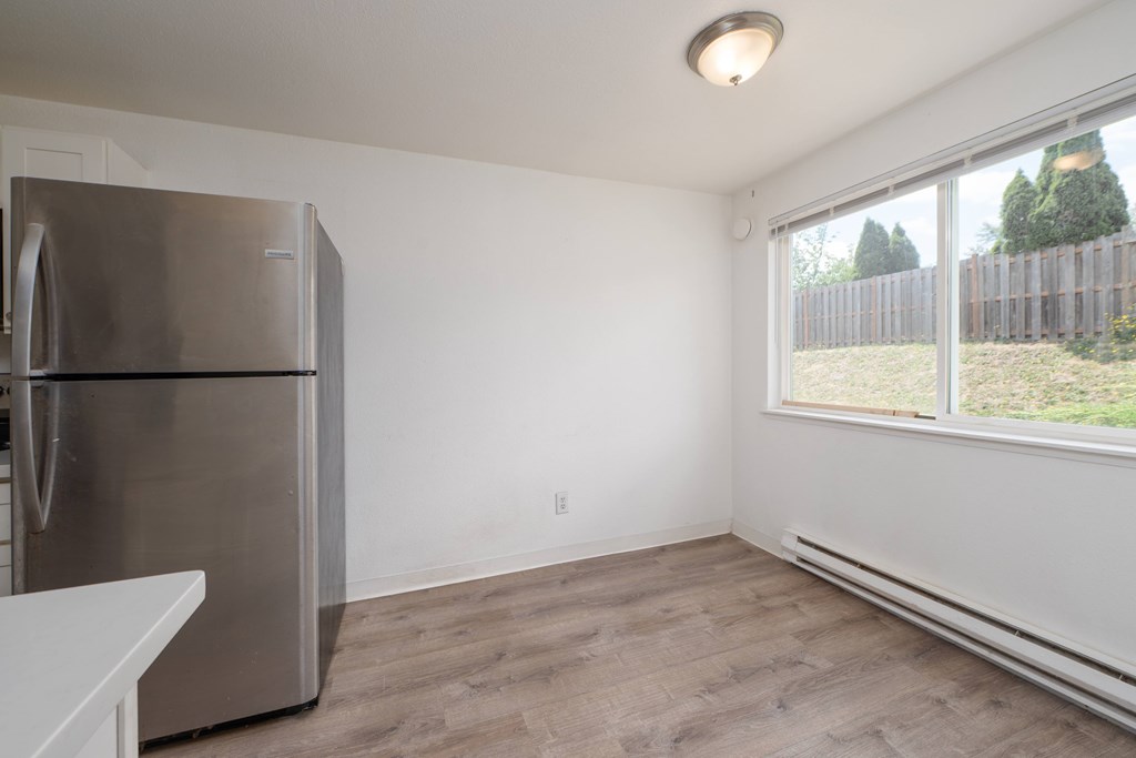 A kitchen with a stainless steel refrigerator and wooden flooring.