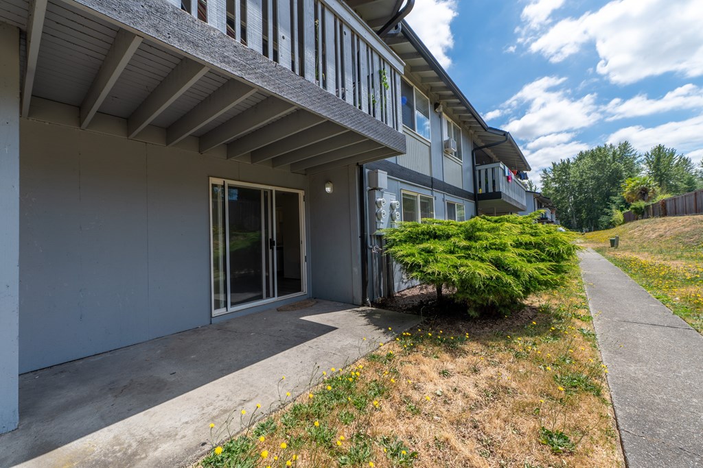 A building with a balcony and a bush in front.