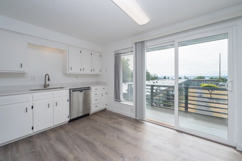 A kitchen with white cabinets and a wooden floor.