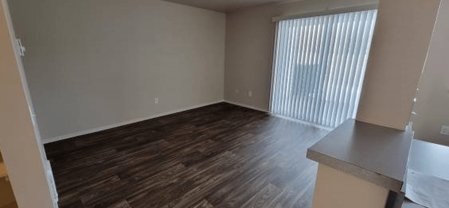 an empty living room with wood flooring and a window