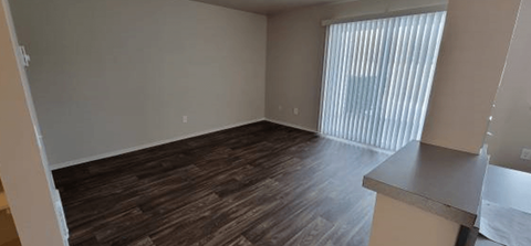 an empty living room with wood flooring and a window