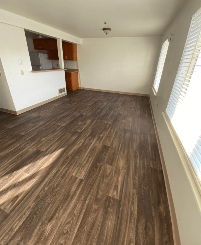 an empty living room with a wooden floor and white walls