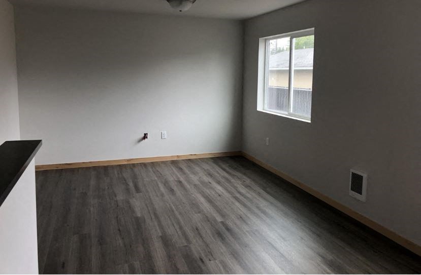 an empty room with wooden floors and a window