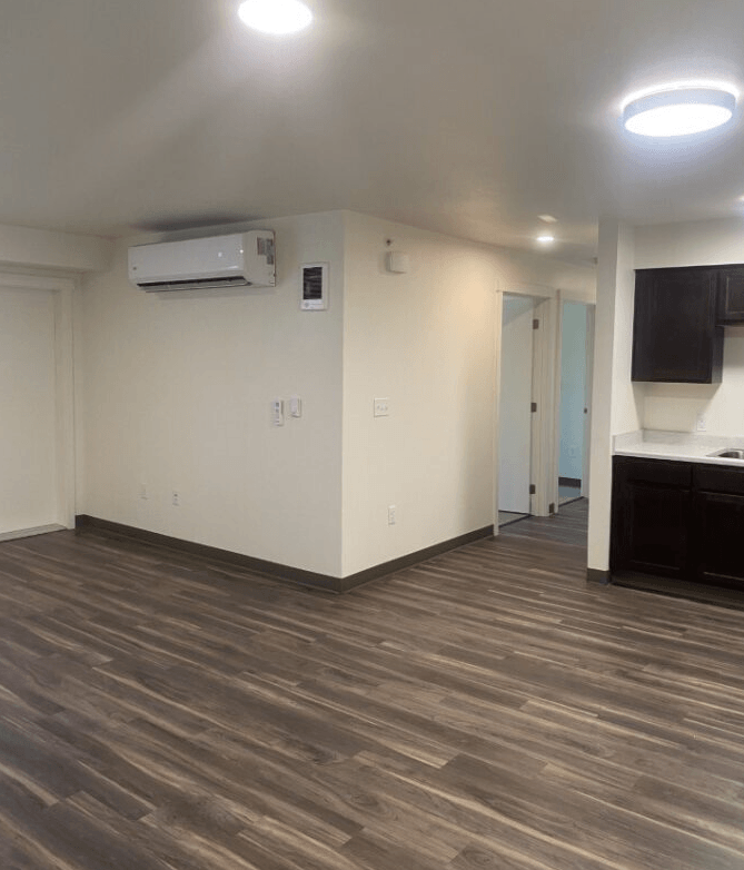 an empty living room with white walls and a kitchen