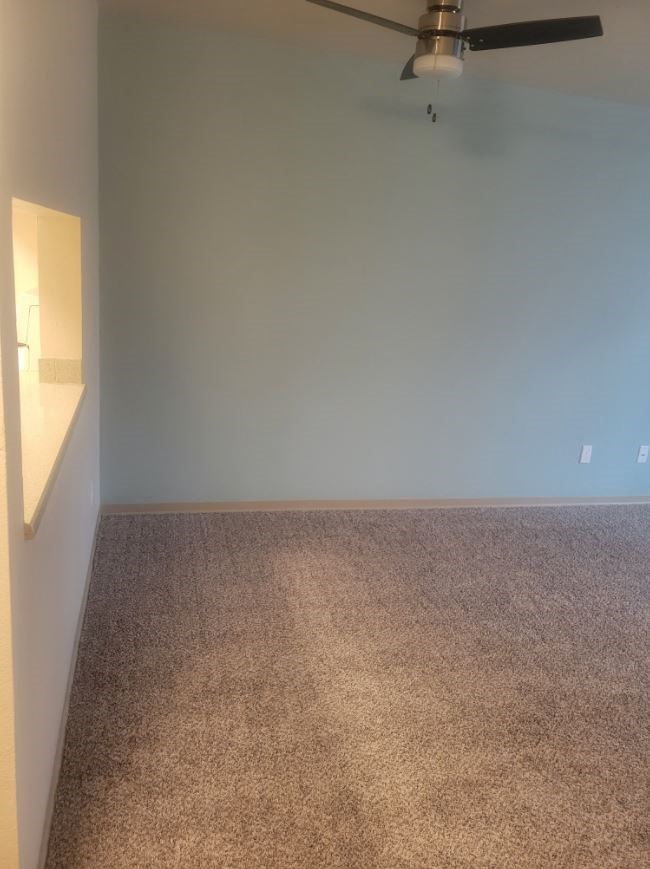 an empty room with a ceiling fan and a white wall