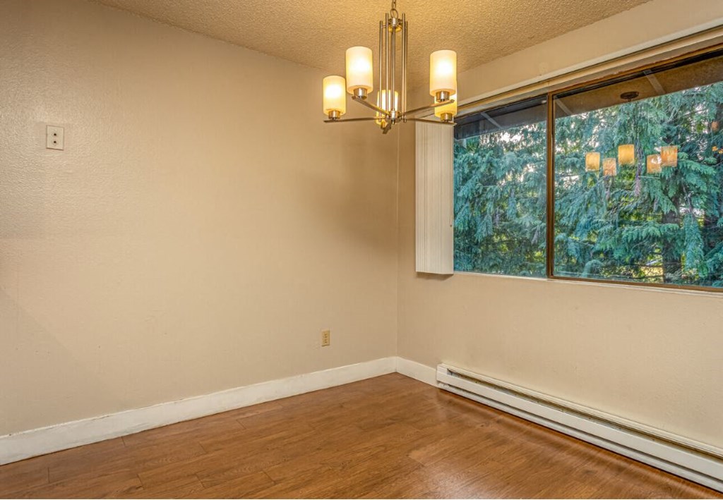 an empty living room with a large window and a chandelier