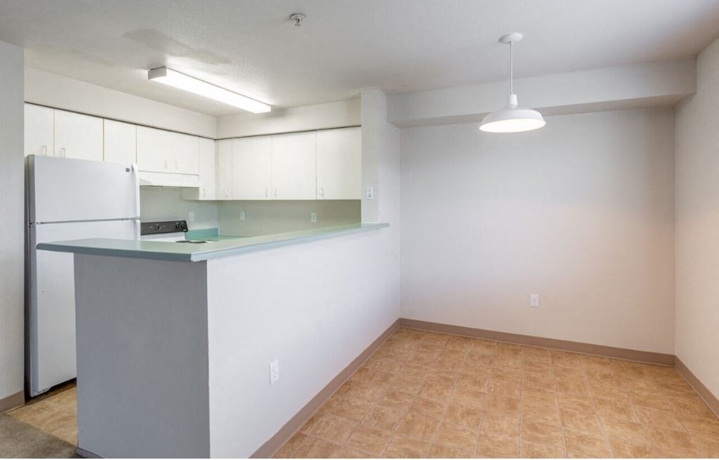 an empty kitchen with a counter top and a refrigerator