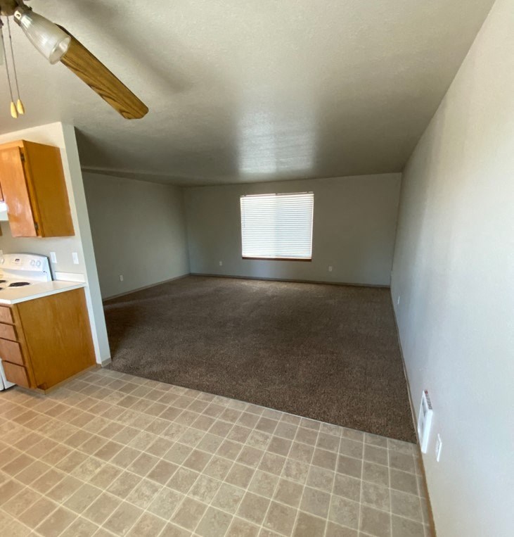 an empty room with a kitchen and a window