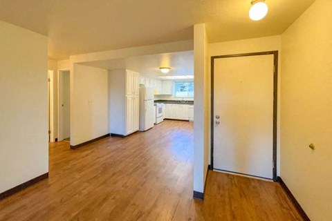 an empty living room and kitchen with a wood floor