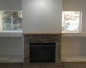 a living room with a brick fireplace and two windows