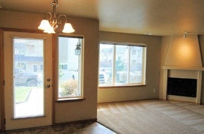 an empty living room with a fireplace and windows