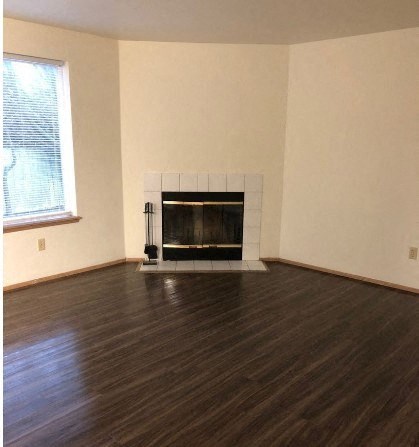 A living room with a fireplace and wood flooring.