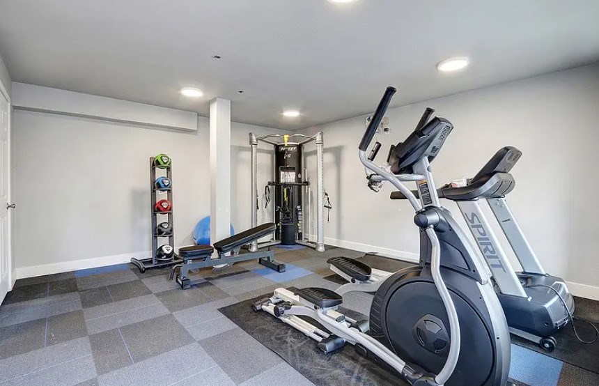 A spacious home gym with a variety of equipment including a treadmill, elliptical trainer, and weights.