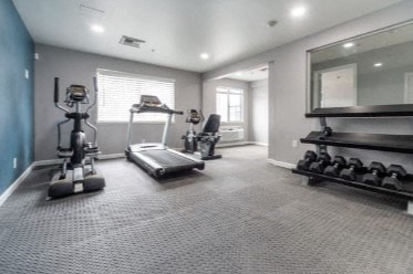 the gym has plenty of exercise equipment and a mirror