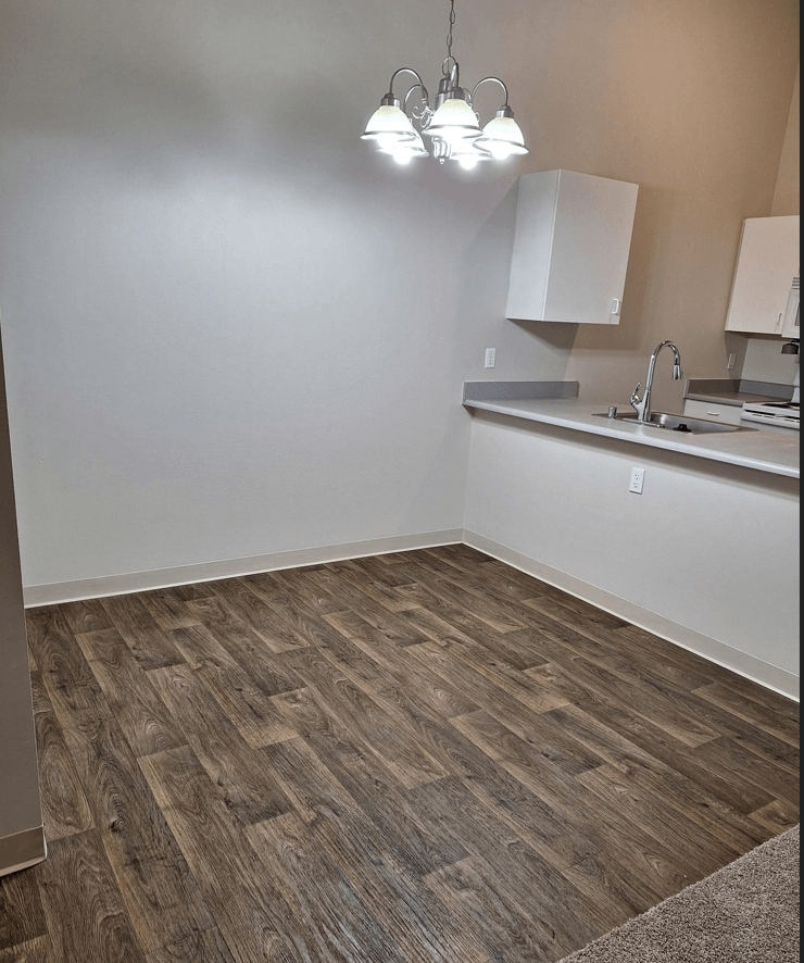 an empty kitchen with wood flooring and white walls
