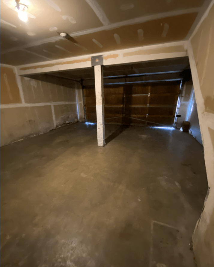 a basement with a concrete floor and a garage door