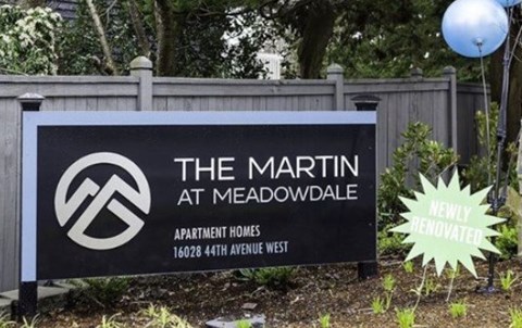 a sign for the at meadowdale in front of a fence