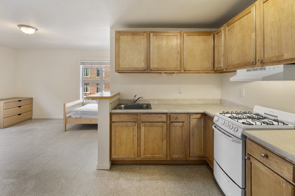 an empty kitchen with white appliances and wooden cabinets
