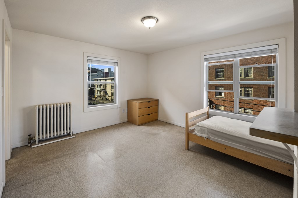 a bedroom with a bed and a radiator and a window
