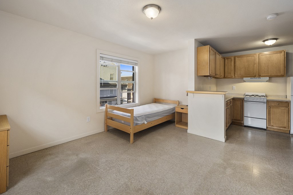 an empty room with a bed and a kitchen