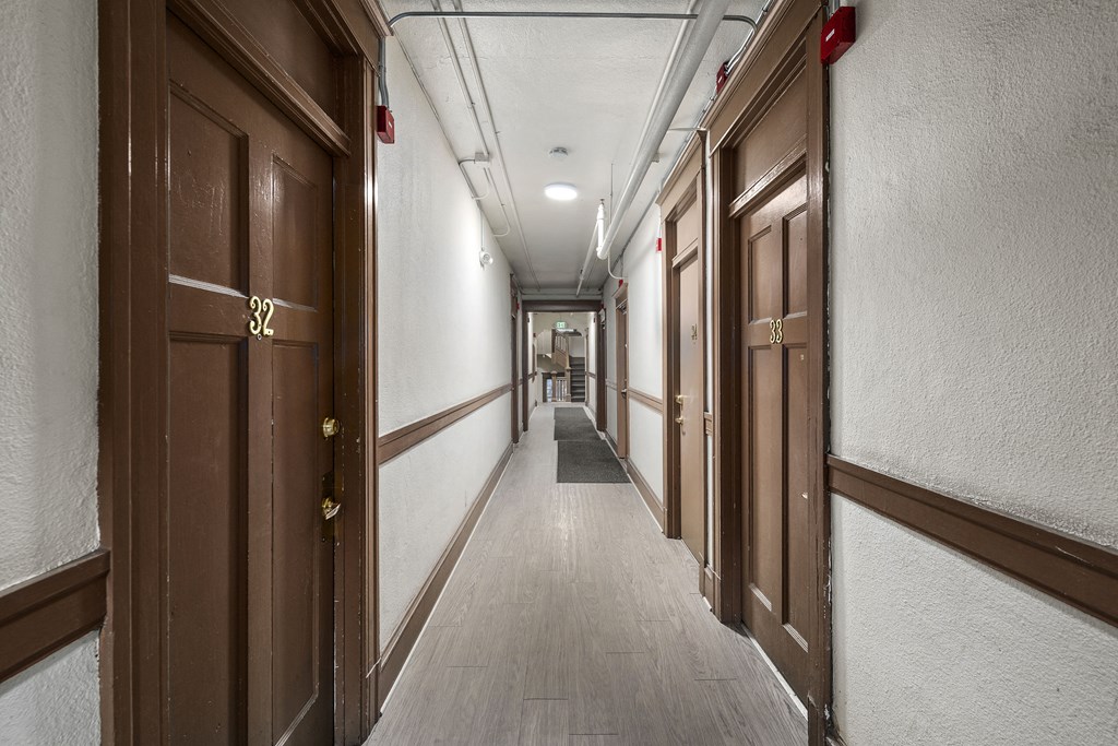 a long corridor with wooden doors and white walls in a building
