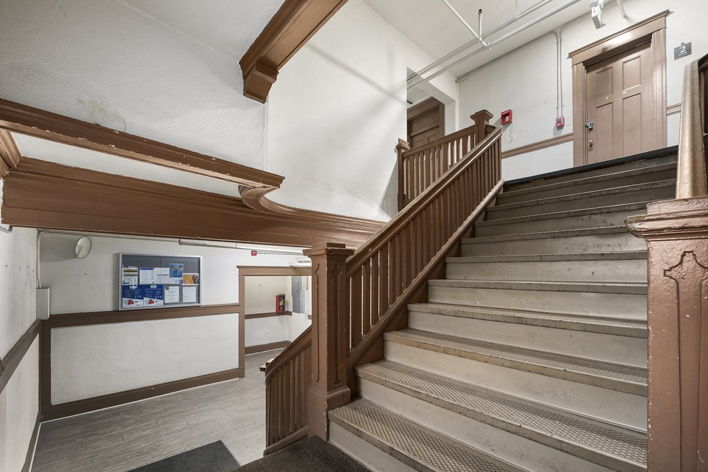 the staircase in the lobby of a building with wooden stairs and a wooden railing
