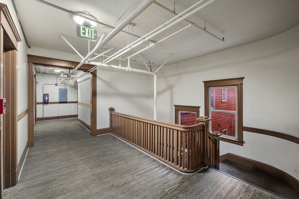 a large hallway with wood floors and white walls and a exit sign