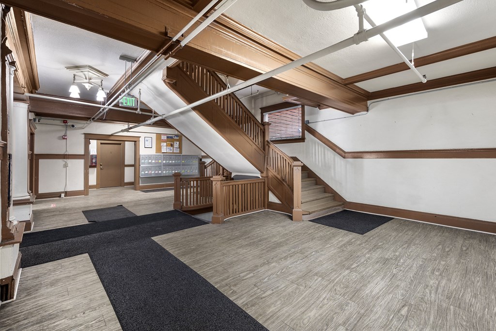 the lobby of a building with stairs and a hallway with rugs