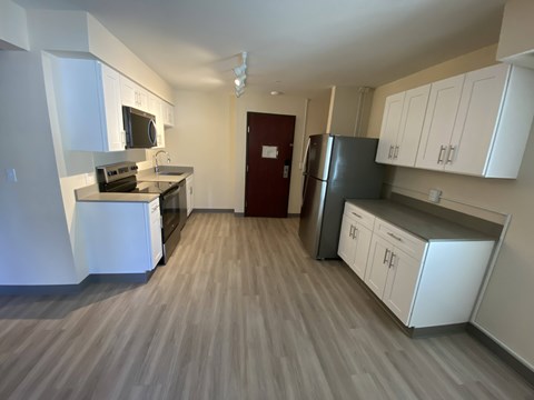 A kitchen with white cabinets and a red door.