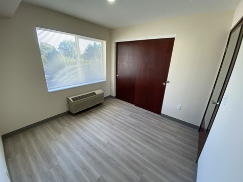A room with a wooden floor and a window with blinds.
