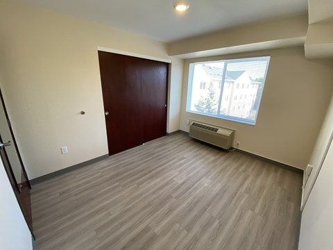 A room with a brown door and a window with a view of a building outside.