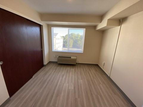 A room with a brown door and a window with a view of trees and a building outside.