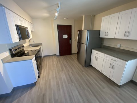 A kitchen with white cabinets and a red door.