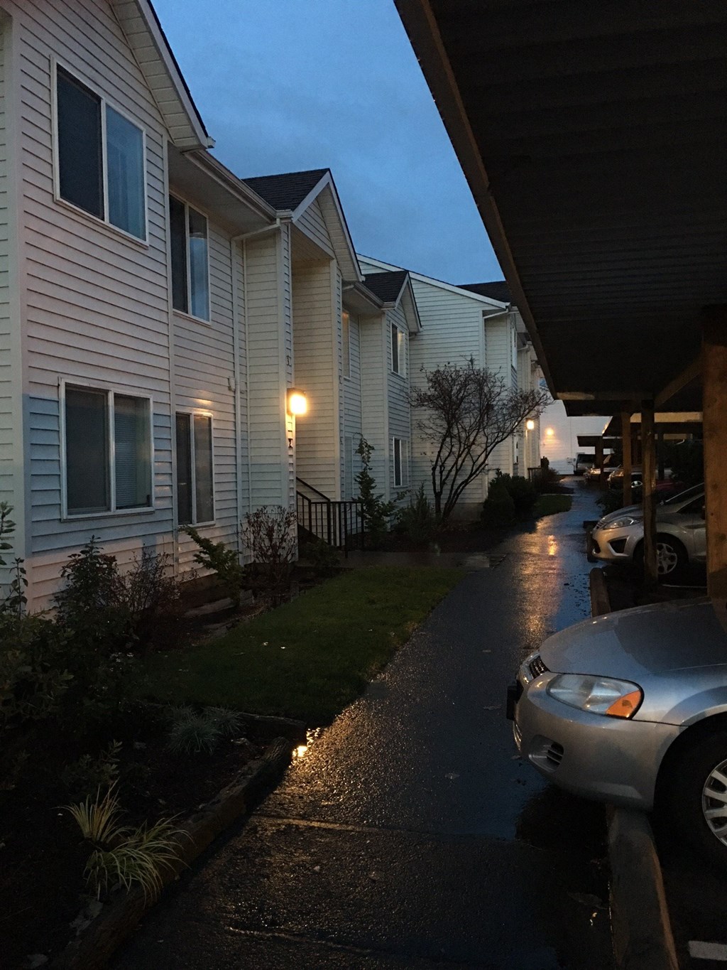 a rain soaked street in front of a house at night