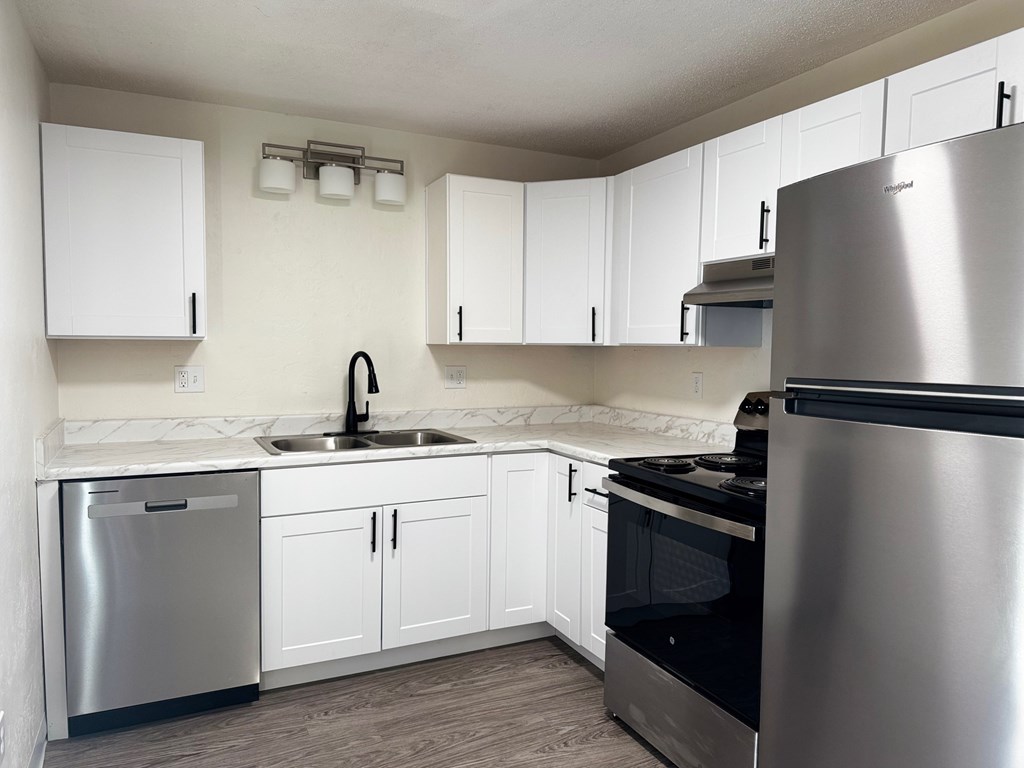 A kitchen with white cabinets and a stainless steel refrigerator.