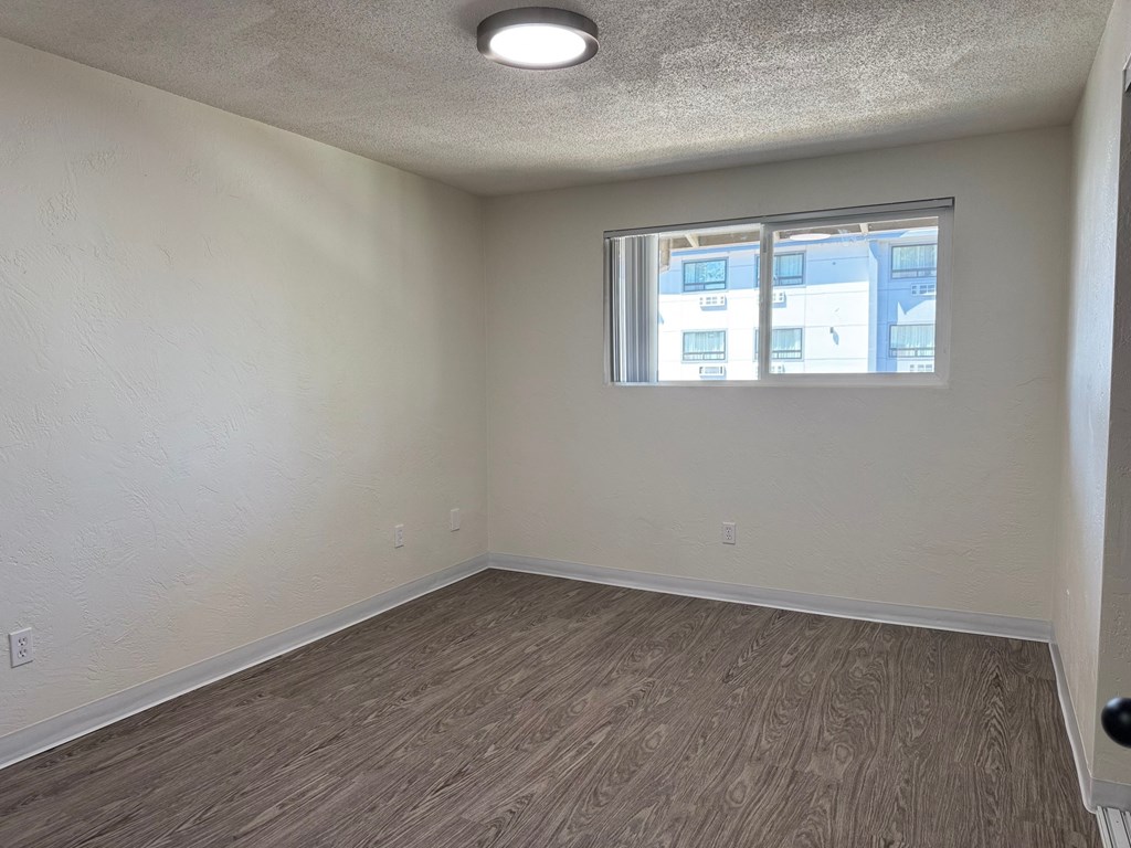 A room with a window and a wooden floor.