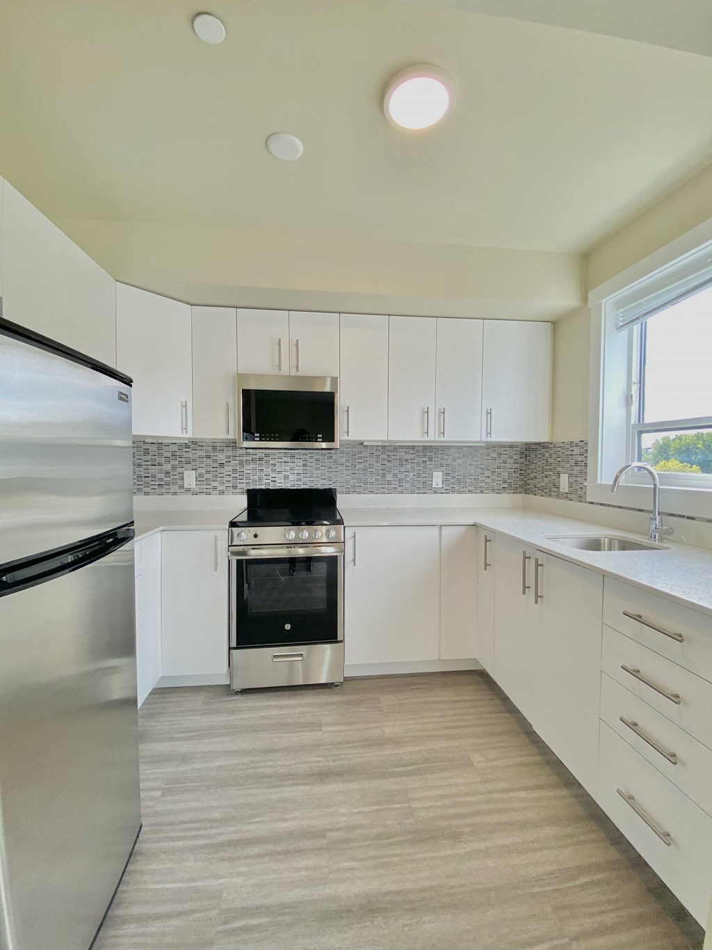 a kitchen with white cabinets and stainless steel appliances and a window