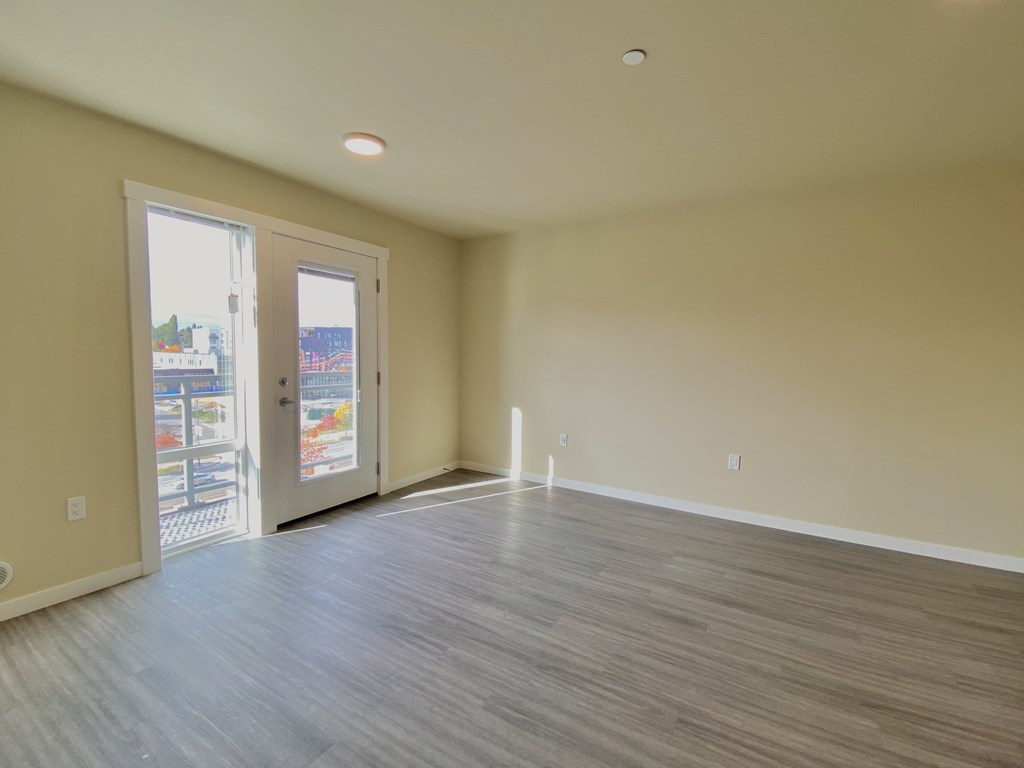 an empty living room with a door to a balcony