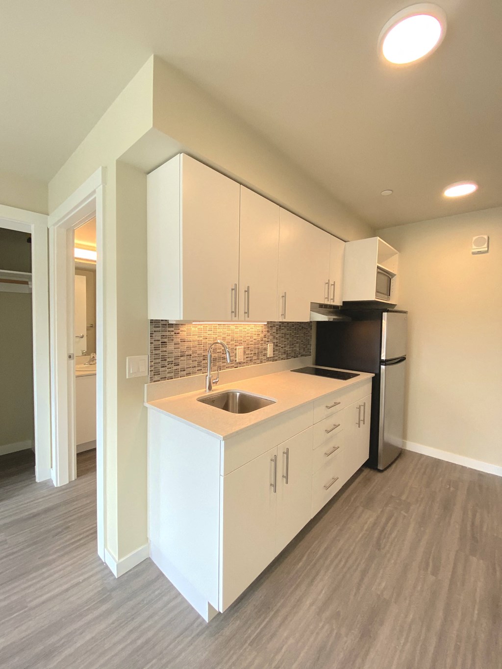 a kitchen with white cabinets and a sink and a refrigerator