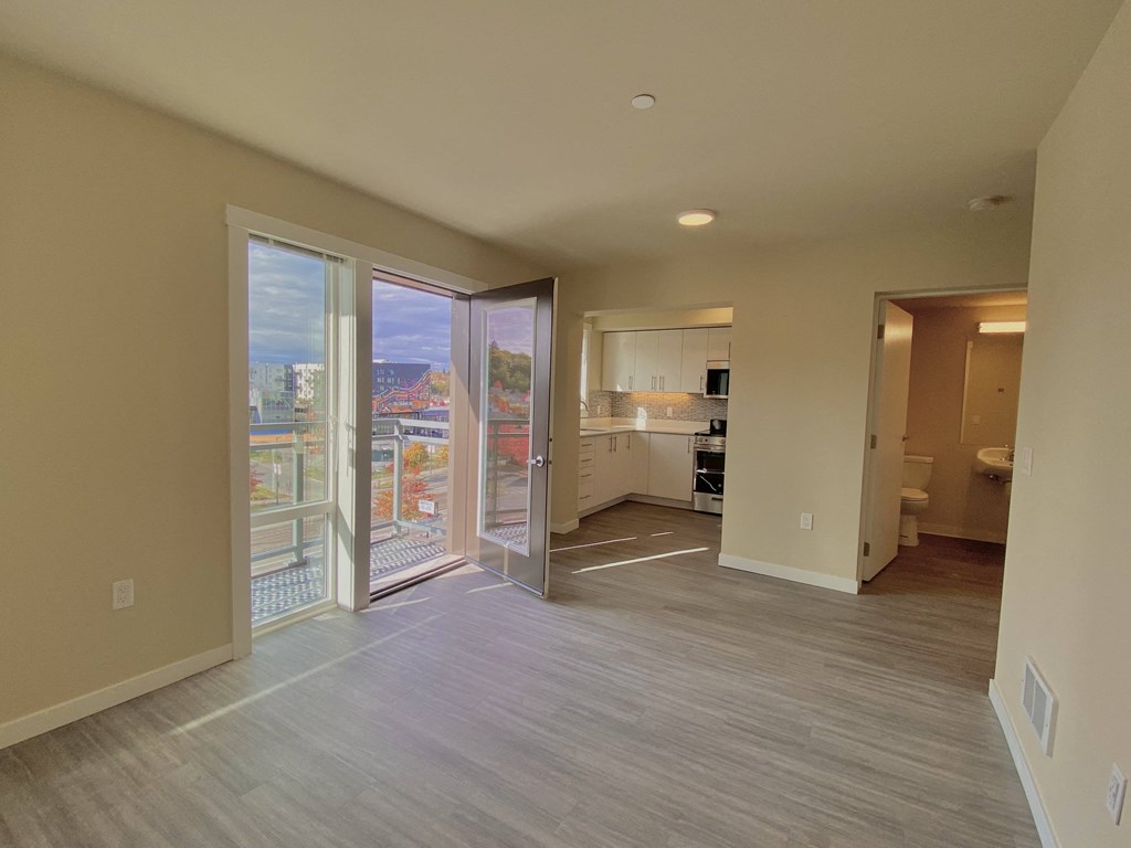 an empty living room with sliding glass doors and a kitchen