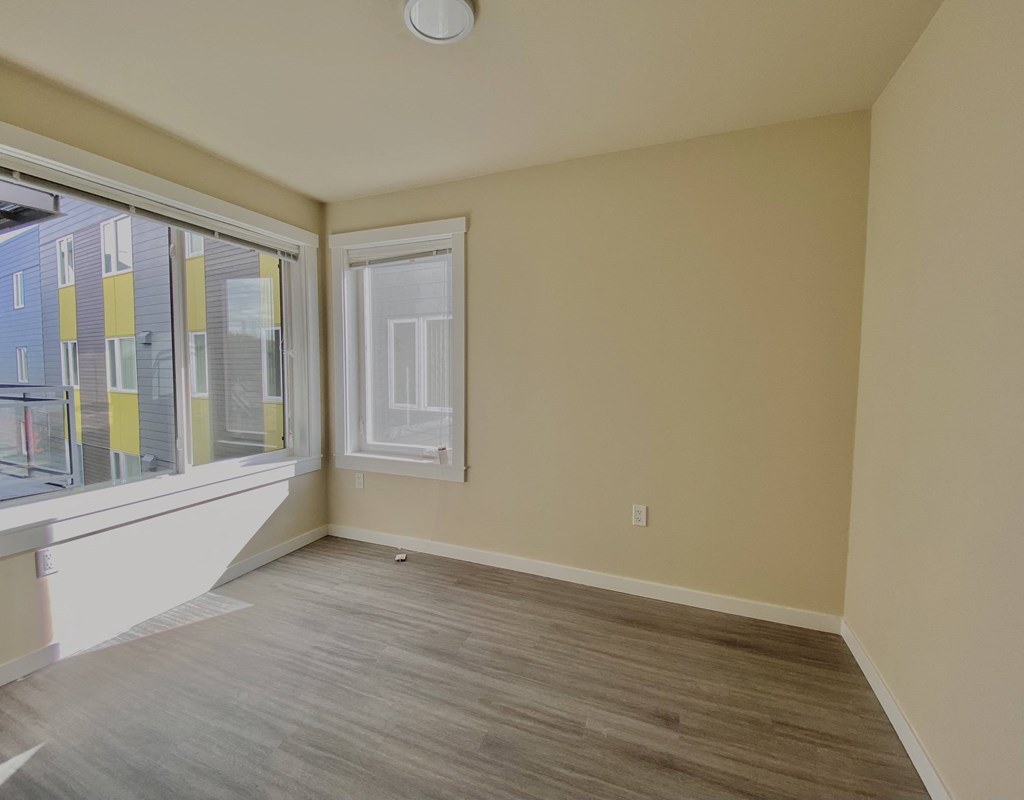 an empty living room with a large window and wood flooring