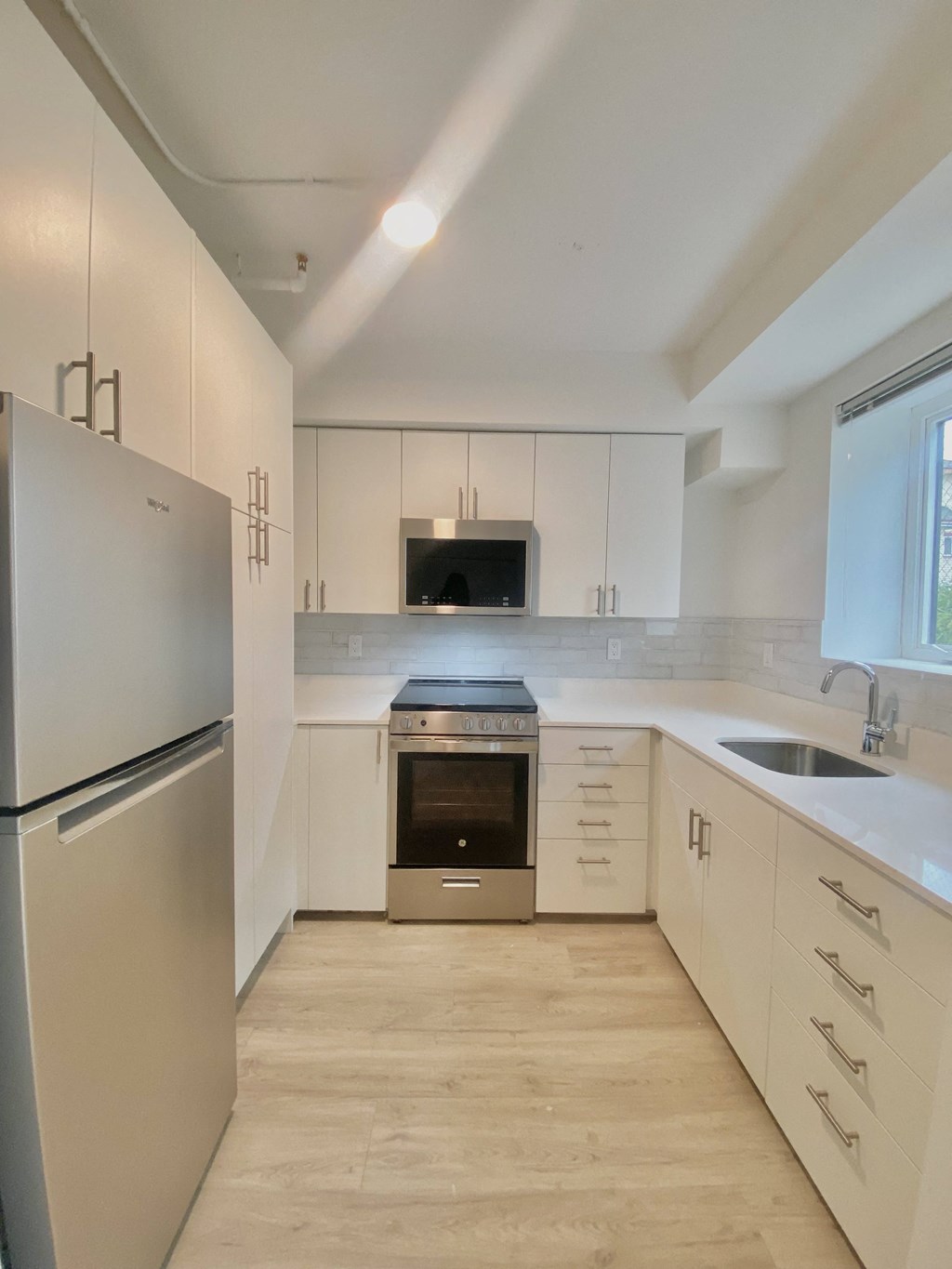 a renovated kitchen with white cabinets and stainless steel appliances
