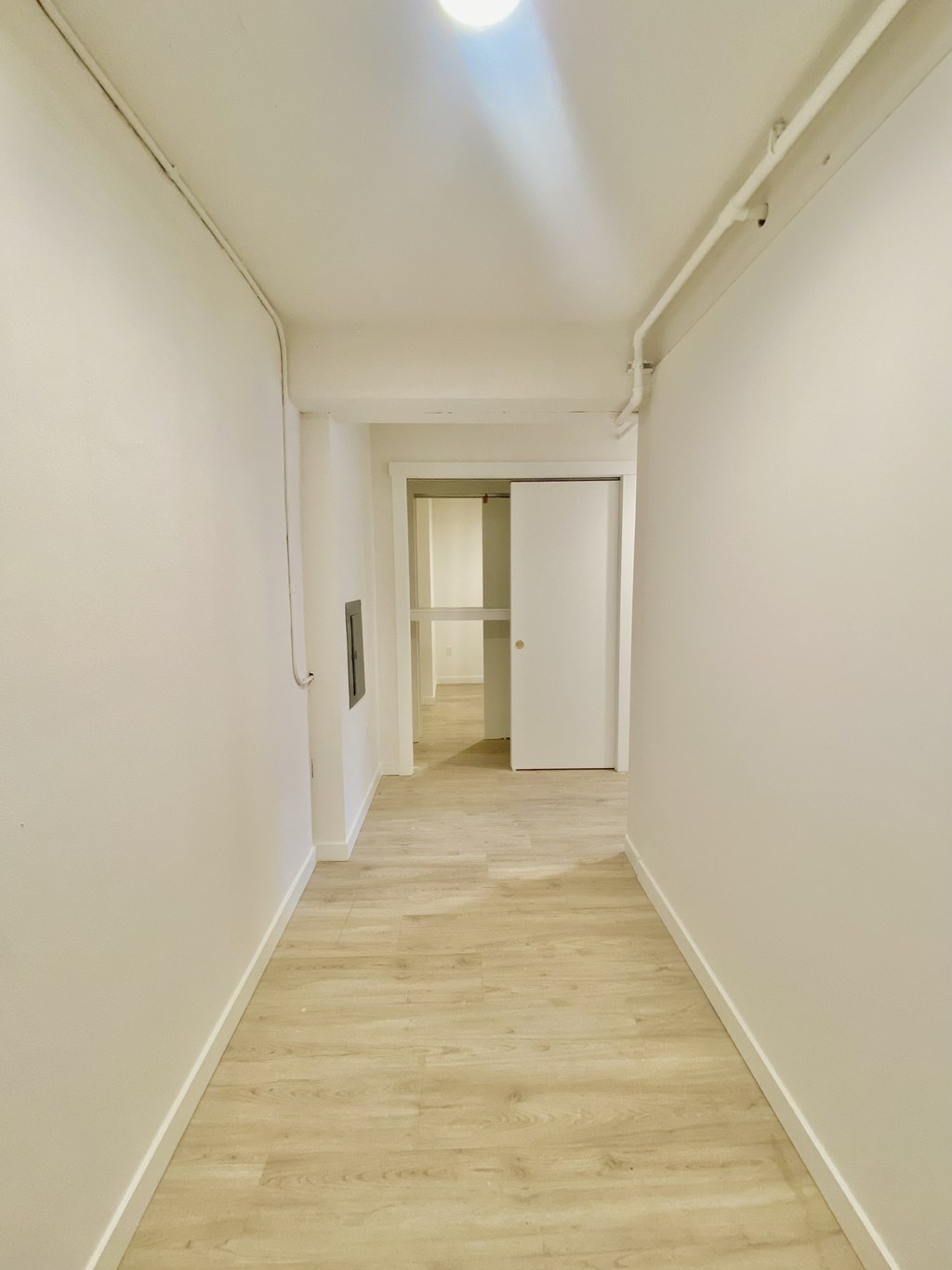 a living room and hallway with white walls and wooden floors