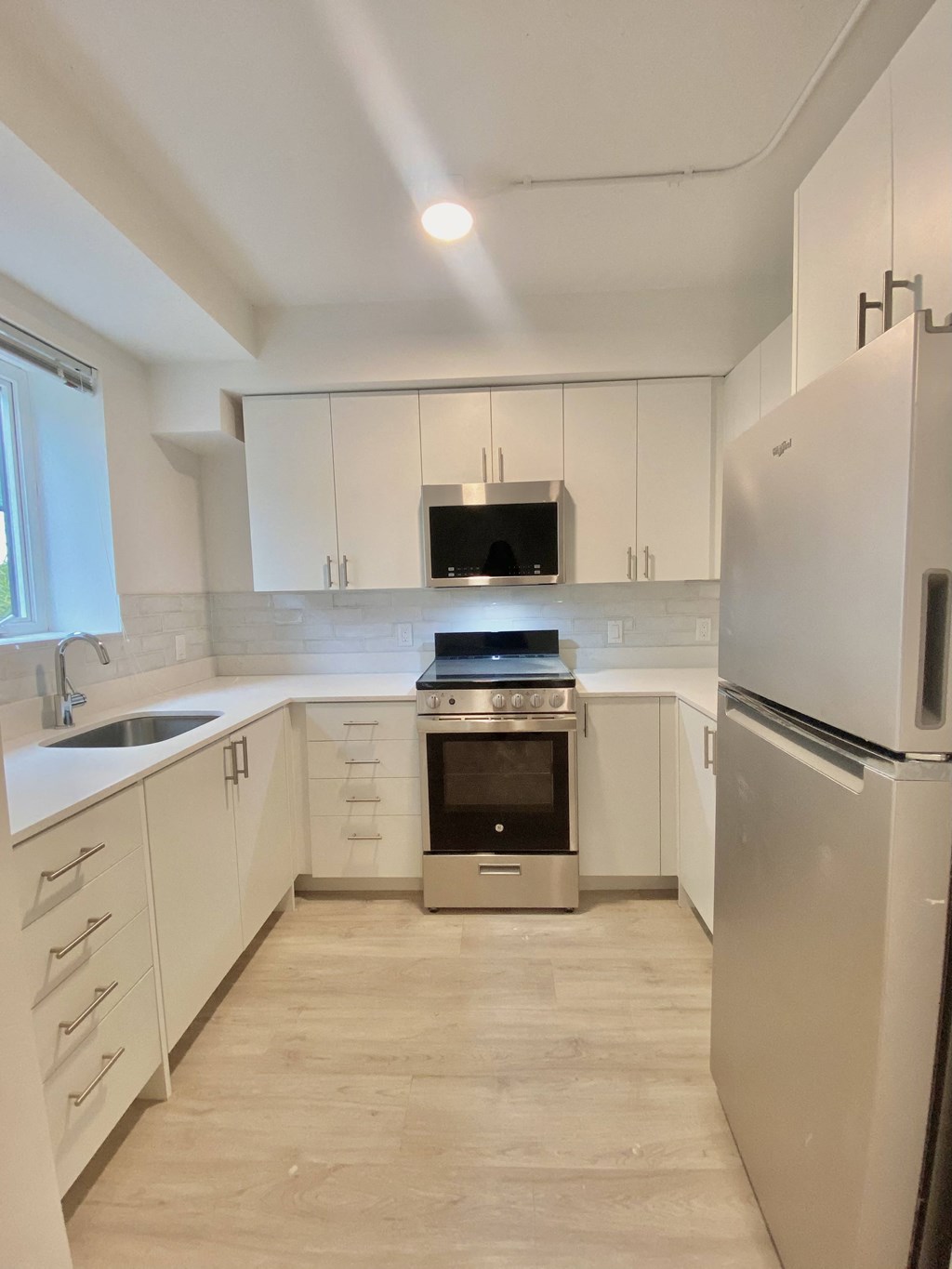 an empty kitchen with white cabinets and stainless steel appliances